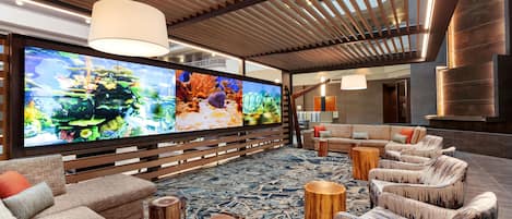 Una sala de estar moderna con un televisor de pantalla plana grande, asientos cómodos y una estructura de techo de madera.