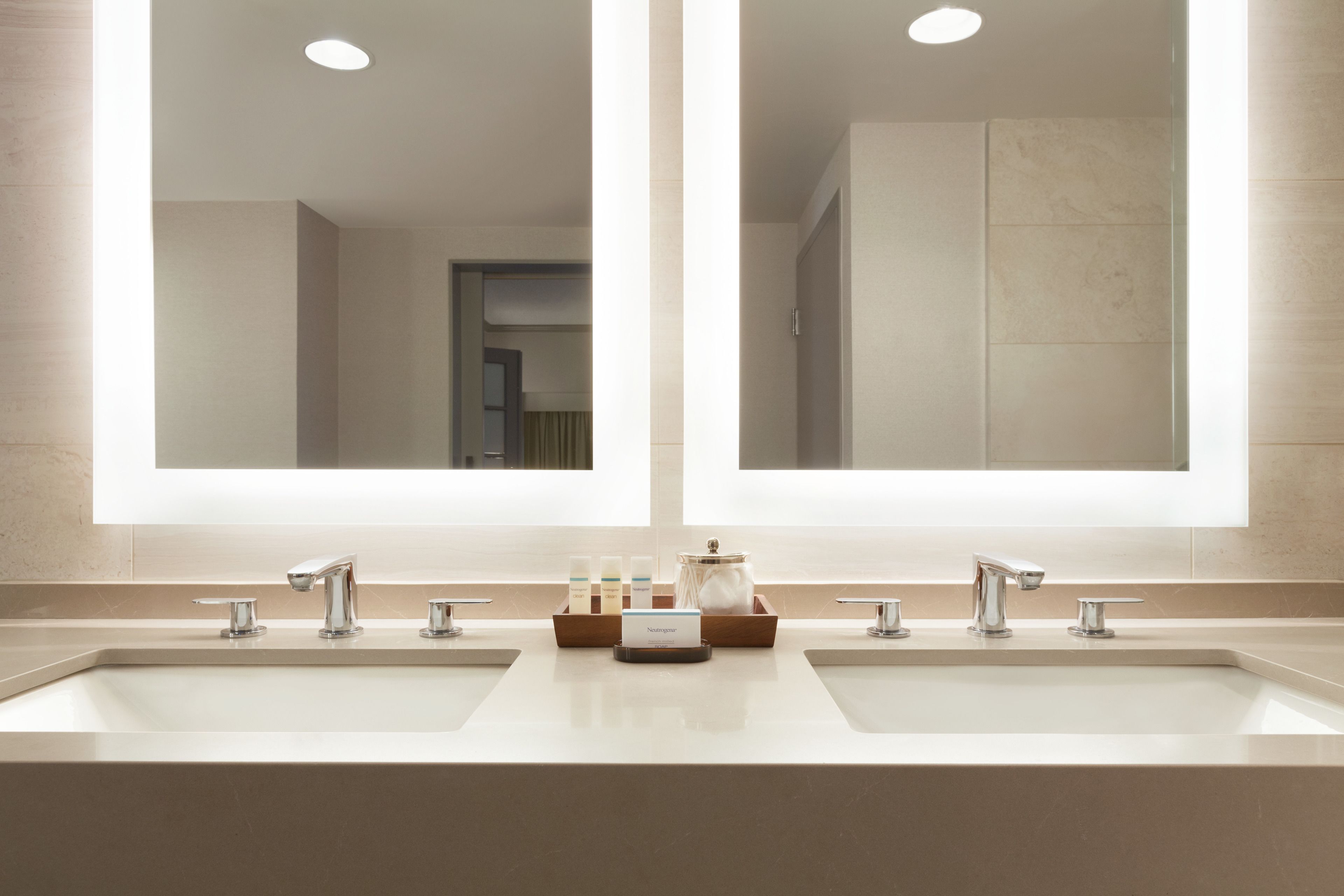 A modern bathroom with two sinks, large mirrors, and a vanity with toiletries.