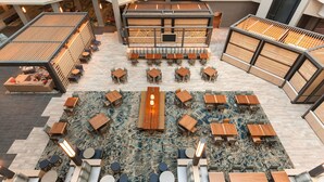A spacious indoor area with multiple seating arrangements, including tables and chairs, and a central wooden table. - Embassy Suites by Hilton Monterey Bay Seaside (Seaside)