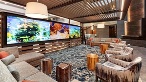 A spacious living area with a large flat-screen TV, comfortable seating, and a wooden ceiling structure. - Embassy Suites by Hilton Monterey Bay Seaside (Seaside)