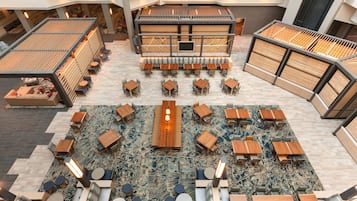 A spacious indoor area with multiple seating arrangements, including tables and benches, and a central area with a long table and chairs.