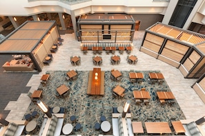 A spacious indoor area with multiple seating arrangements, including tables and benches, and a central area with a long table and chairs.
