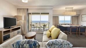A hotel room with a sofa, TV, dining area, and a balcony with a view of the sea. - Embassy Suites by Hilton Monterey Bay Seaside (Seaside)