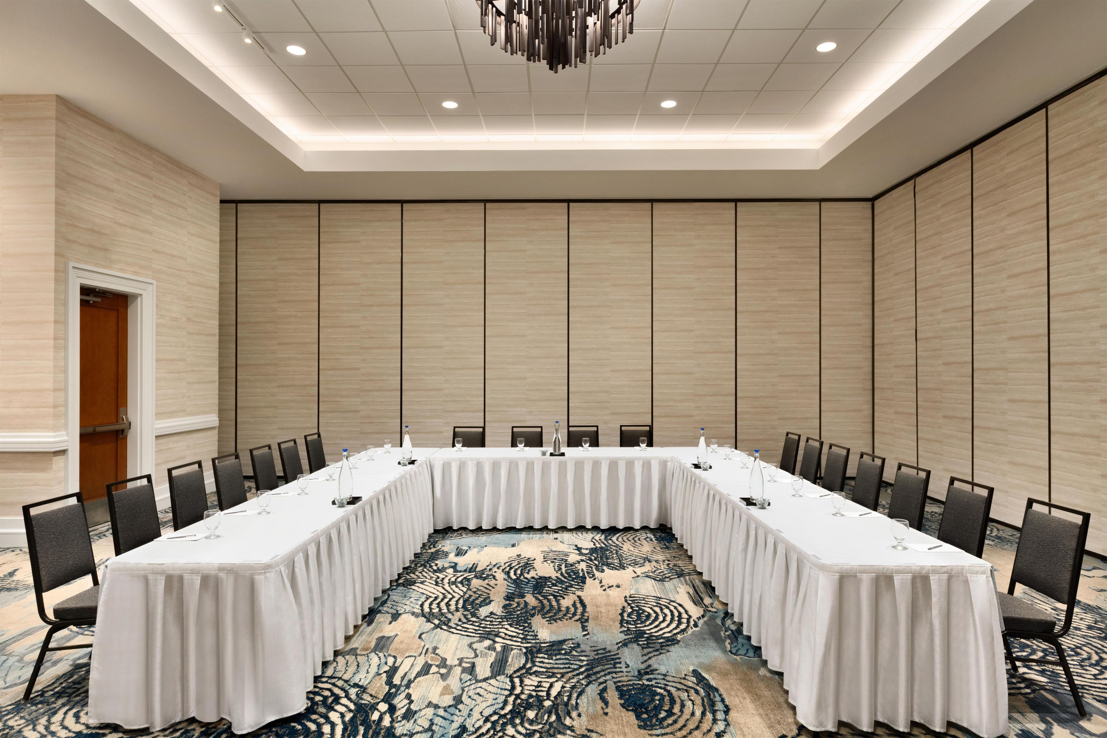 A conference room with a long table, chairs, and a patterned carpet.