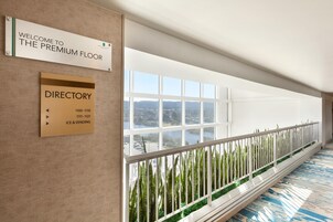 Pasillo de hotel con un cartel de directorio, un letrero de bienvenida y vistas al exterior.