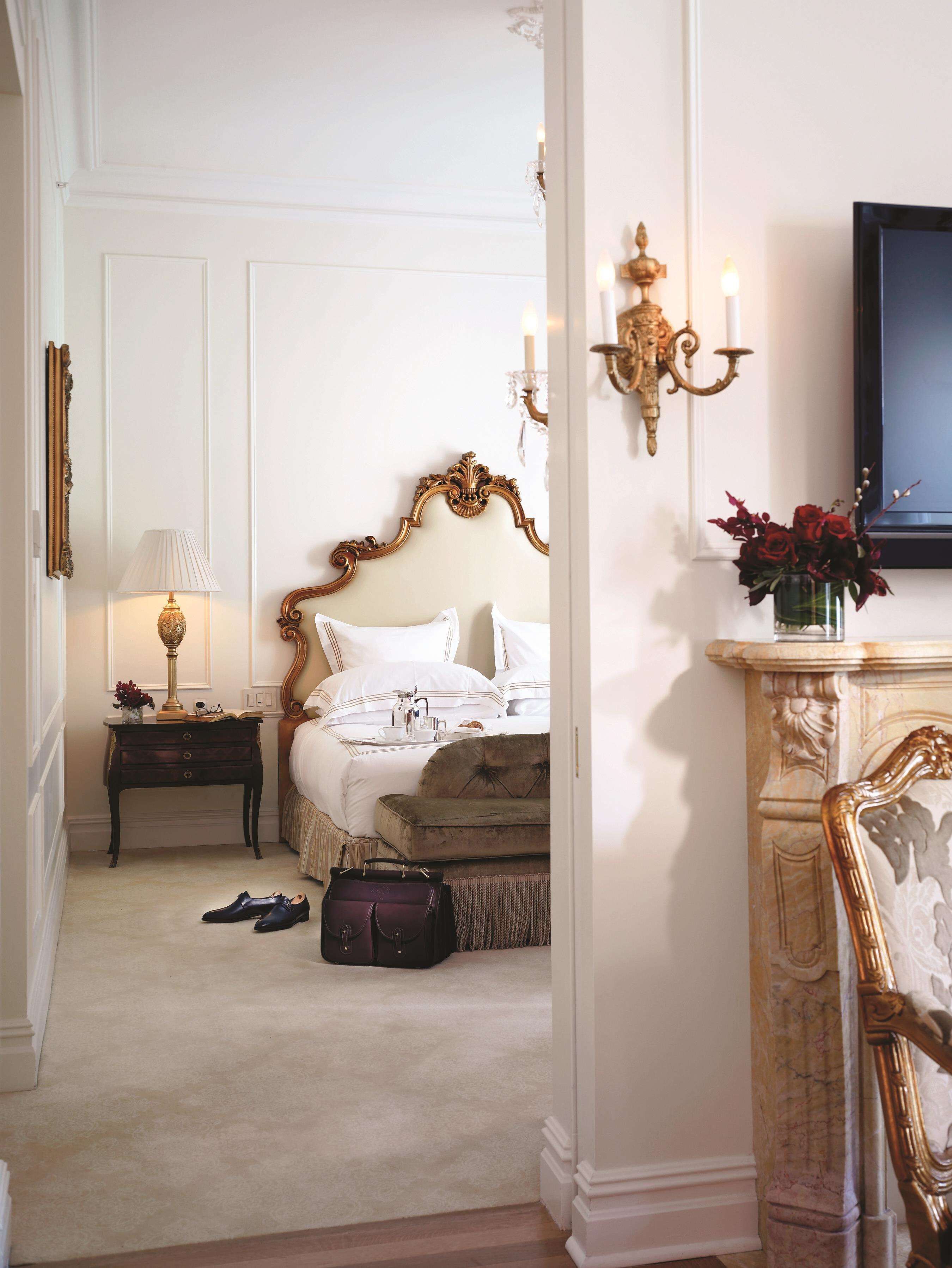 A bedroom with a large bed, a nightstand with a lamp, a dresser, and a mirror.