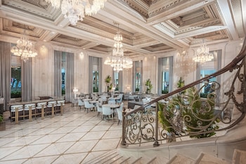 An opulent lobby with a grand chandelier, large arched windows, and a central floral arrangement on a reflective table. at The Plaza, A Fairmont Hotel