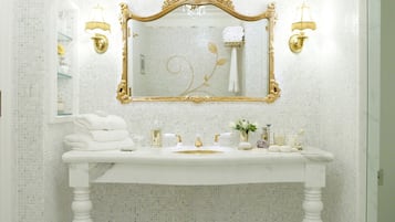 A bathroom with a white vanity, gold-framed mirror, and two wall-mounted lamps.