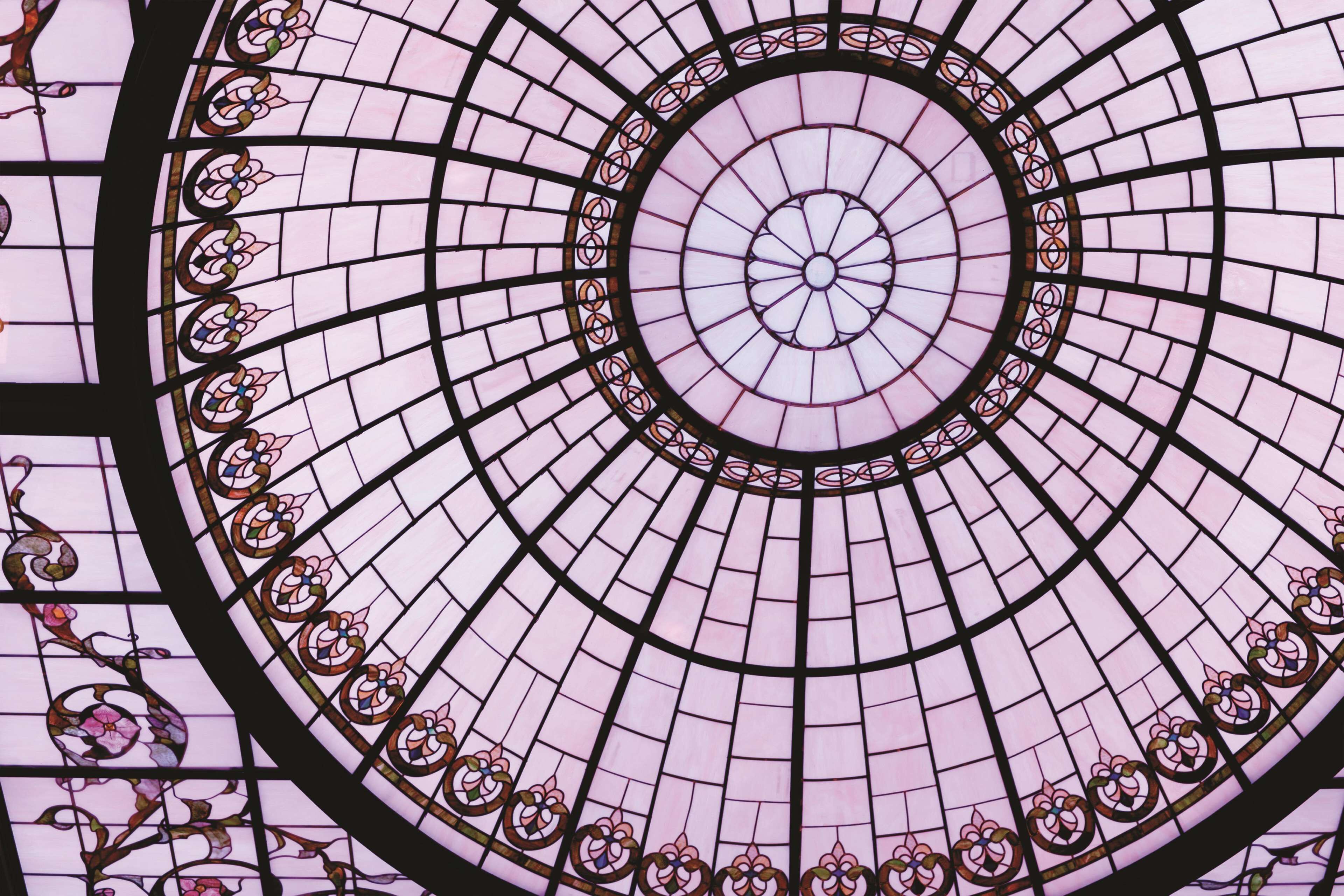 Un techo de vitral circular con intrincados diseños florales y un motivo central.