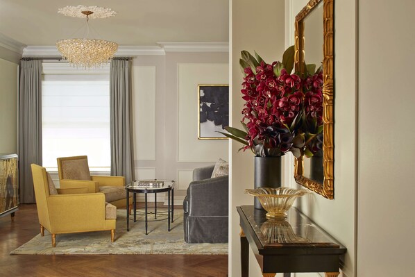 A living room with a yellow armchair, a grey sofa, a chandelier, and a vase with flowers. - The Plaza, A Fairmont Hotel (New York)