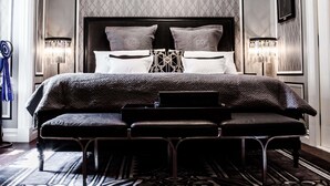 A luxurious bedroom with a large bed, a chandelier, and a patterned rug.
