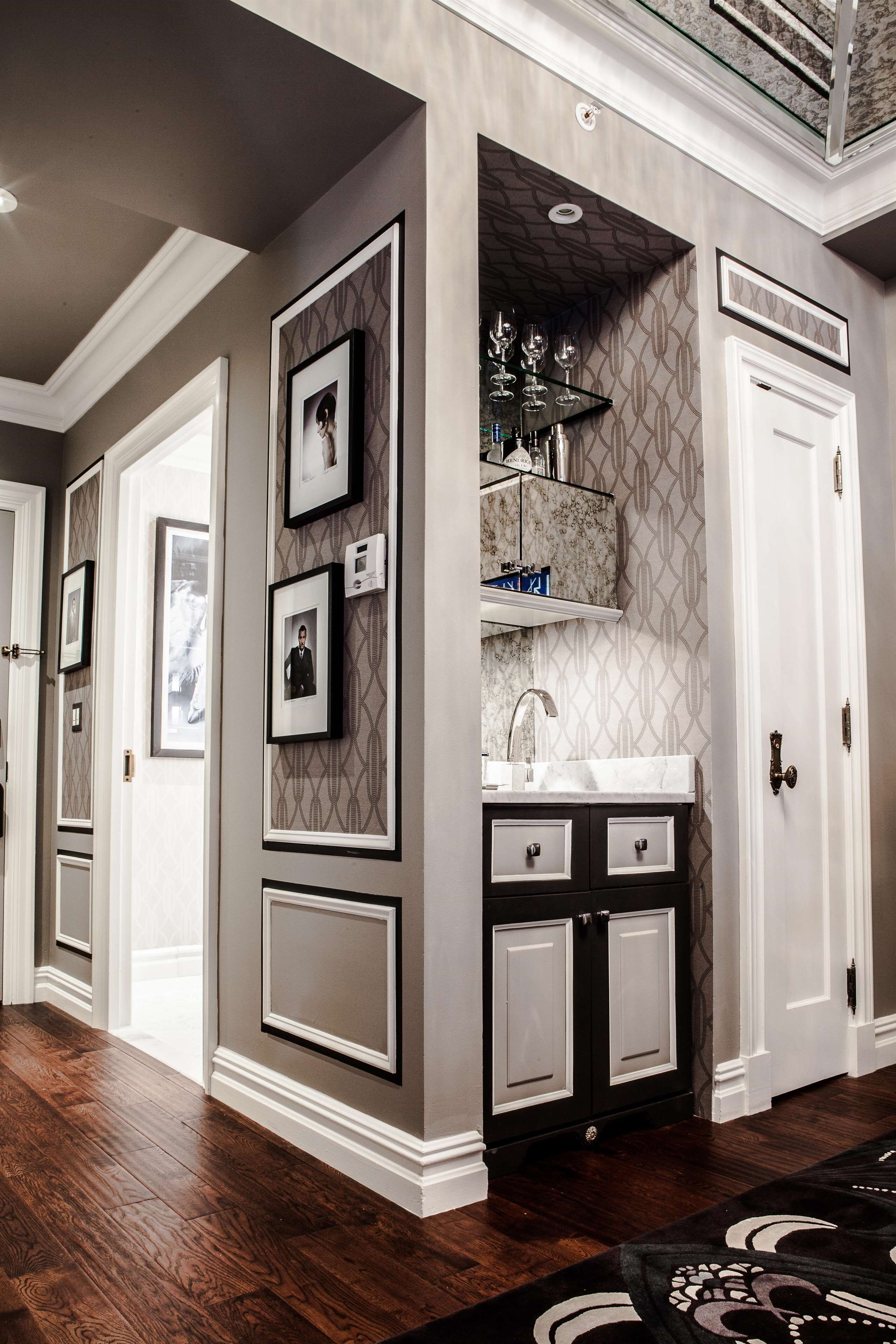 A hallway with a built-in vanity, framed pictures, and a patterned wall.