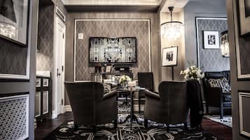 A formal dining area with a chandelier, a large wall-mounted TV, and a patterned rug.