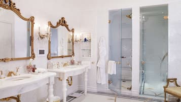 A luxurious bathroom with two sinks, a large mirror, and a glass shower enclosure.