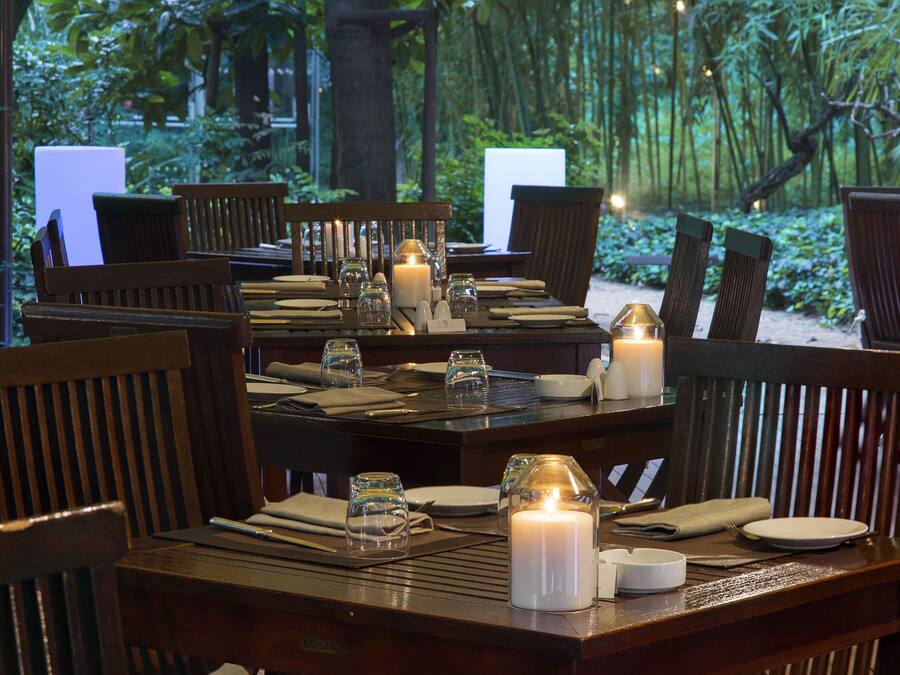 Un espace repas avec des tables et des chaises en bois, des bougies et de la verrerie.