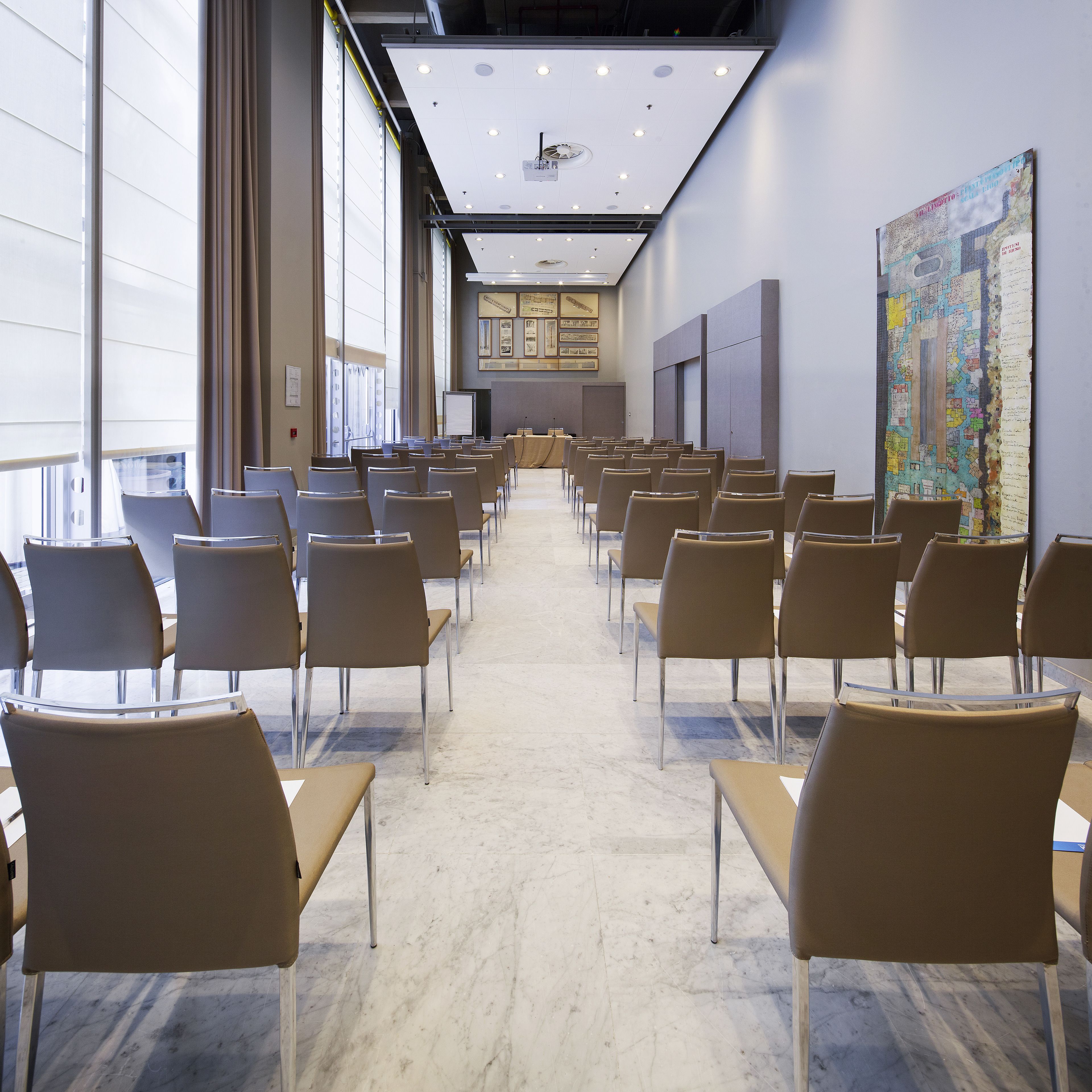 A conference room with rows of chairs, a large window, and a map on the wall.