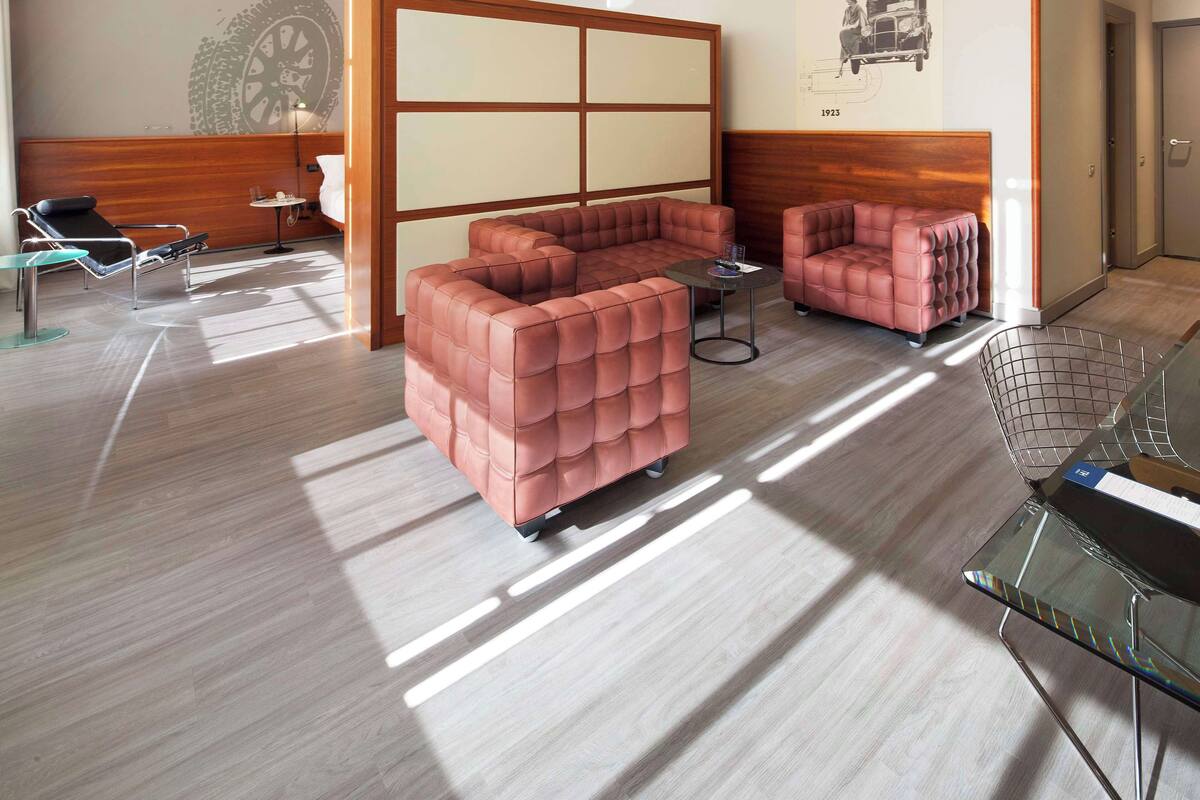 Habitació d'hotel moderna amb un llit gran, dos sofàs, una taula petita i una cadira.