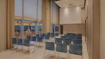 A conference room with rows of chairs, large windows, and a table with a projector.