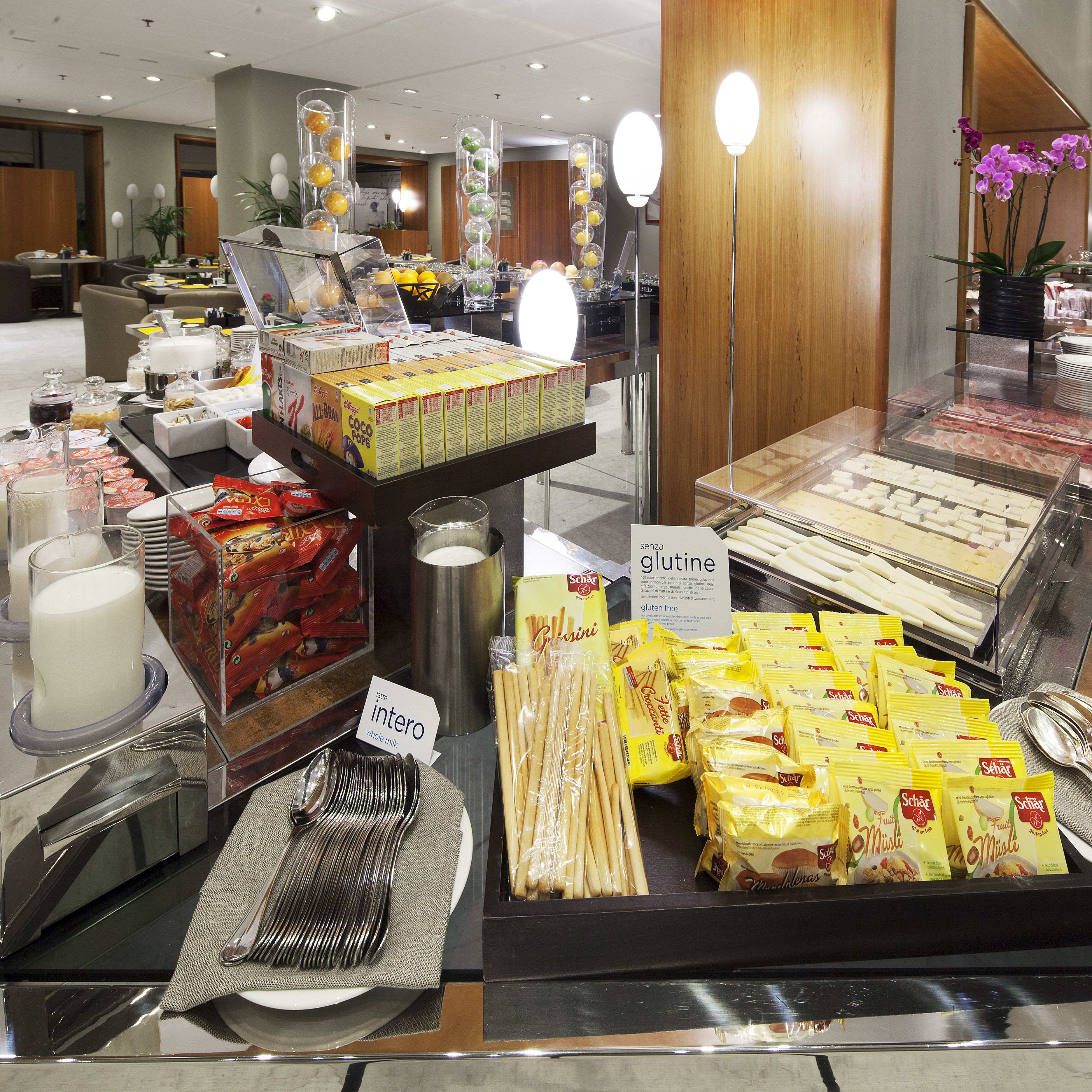 Un bufé con diversas opciones de comida, incluyendo un letrero que indica opciones sin gluten.