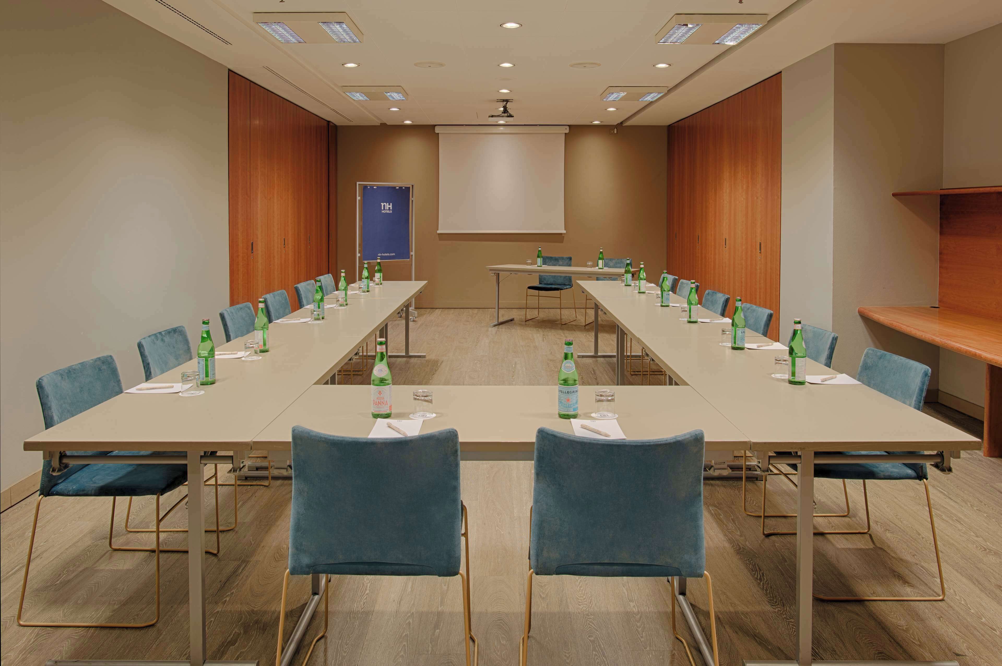 A conference room with a long table, blue chairs, and water bottles.