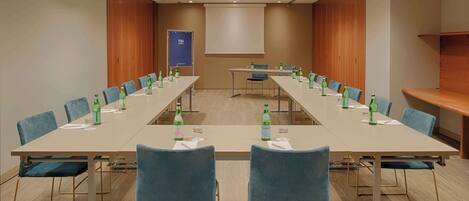 A conference room with a long table, blue chairs, and water bottles.