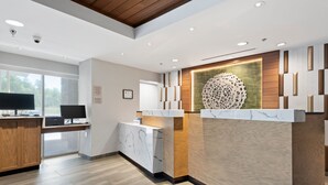 Un espace d’accueil moderne avec un comptoir en marbre, des éléments décoratifs en bois et un grand panneau mural décoratif.