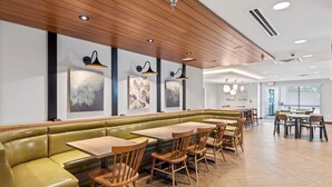 Un restaurant doté d’un espace salon avec des banquettes vertes, des tables et des chaises en bois.