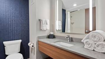 Un baño moderno con inodoro, lavamanos y espejo.