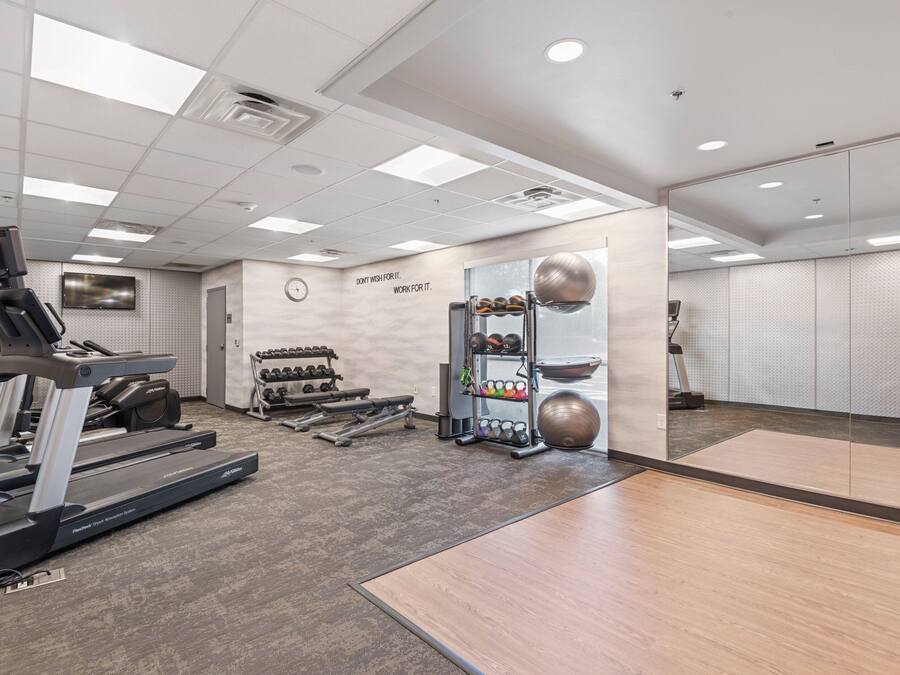 A gym with a treadmill, weights, and exercise balls.