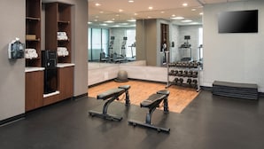 Une salle de sport équipée de matériel d’exercice, avec un miroir et un téléviseur fixé au mur.