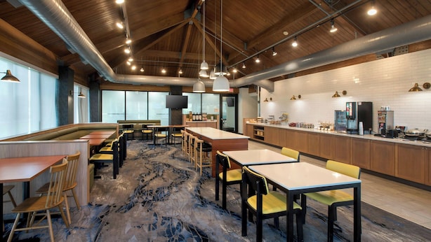 Un vaste espace dédié à la salle à manger, avec de hauts plafonds, des conduits apparents et un tapis à motifs.