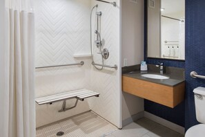 A modern bathroom with a shower, grab bars, a sink, and a toilet.