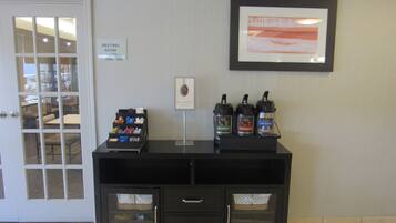 A reception area with a coffee station, a framed picture, and a sign indicating a meeting room.