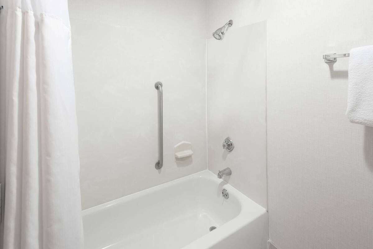 A white bathtub with a showerhead, a grab bar, and a towel rack.