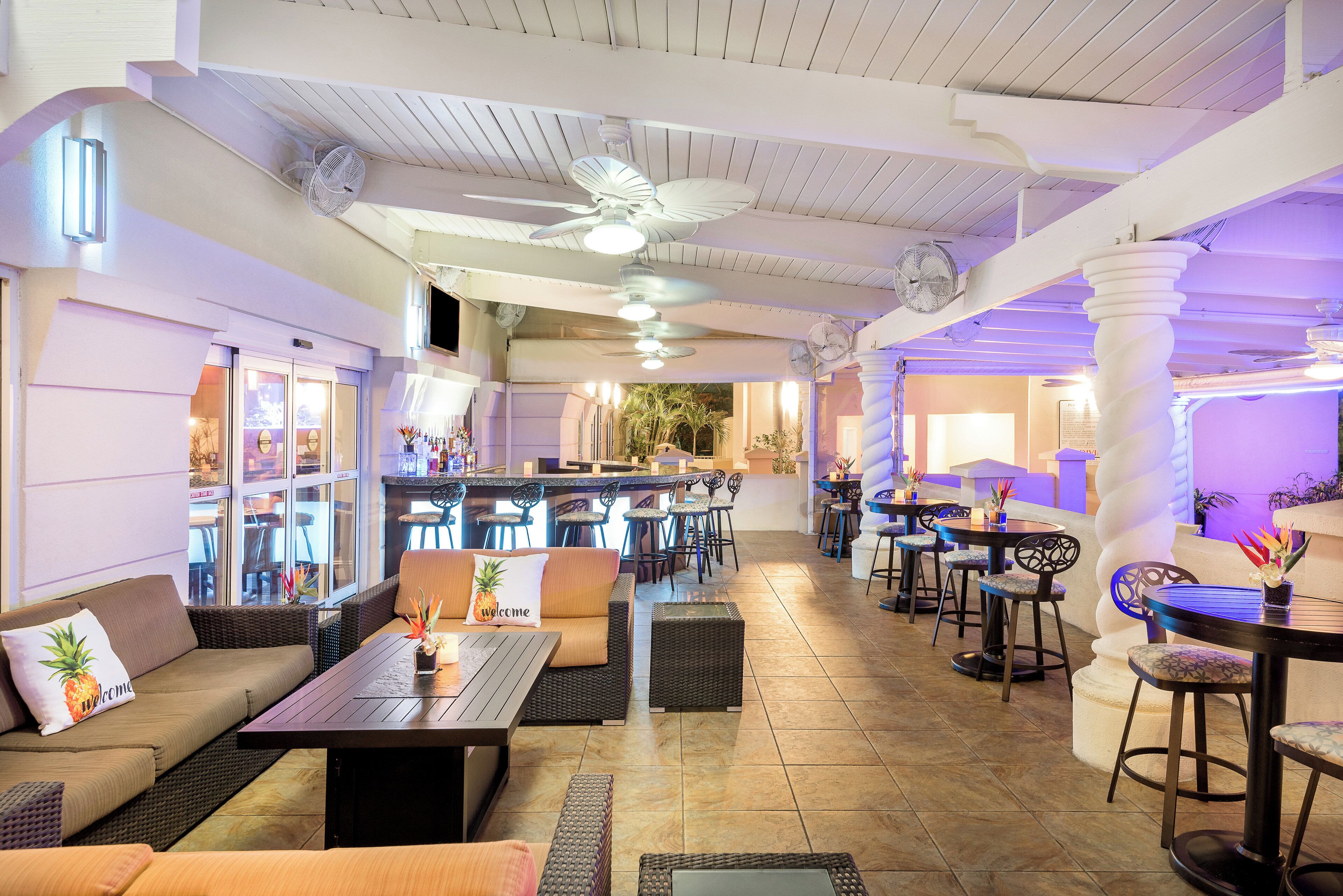Un vaste espace intérieur aménagé avec différents types de sièges, notamment des canapés et des tables, ainsi qu’un coin bar avec des tabourets.