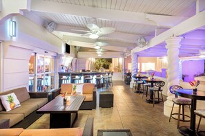 A spacious indoor area with multiple seating arrangements, including sofas and tables, and a bar area with stools. - Holiday Inn Fort Lauderdale Airport by IHG (Hollywood)