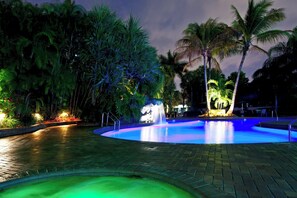 A nighttime swimming pool with a fountain, surrounded by palm trees and illuminated by artificial lighting. - Holiday Inn Fort Lauderdale Airport by IHG (Hollywood)