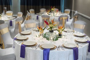 A banquet table set with white plates, gold-rimmed glasses, and silver cutlery. - Holiday Inn Fort Lauderdale Airport by IHG (Hollywood)