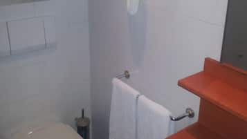 Un bagno con il water, un lavandino, un portascopino e un asciugatore di mani.