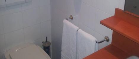A bathroom with a toilet, a sink, a towel rack, and a hand dryer.