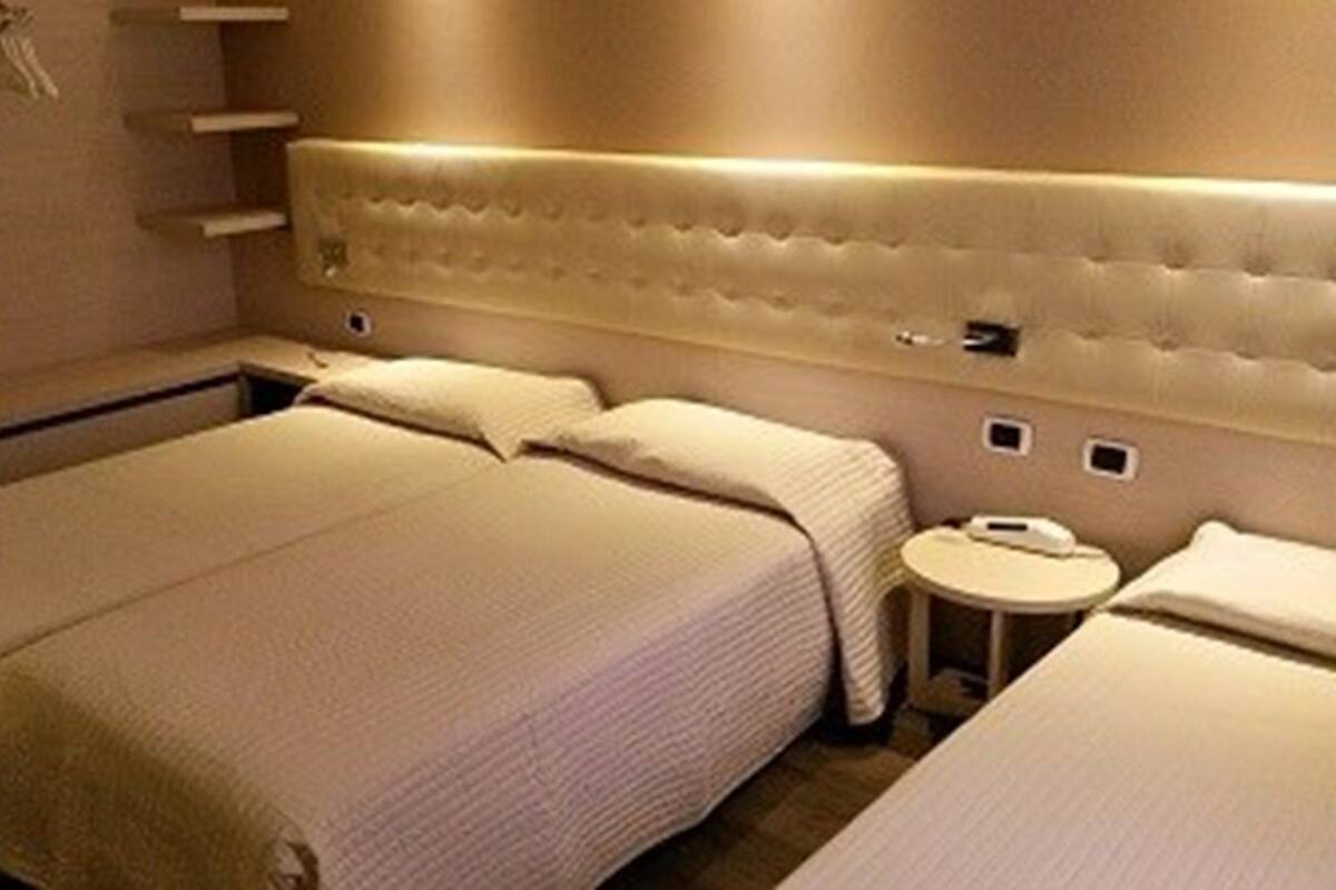 Una camera d'albergo con un letto grande, comodini e un tavolino rotondo.
