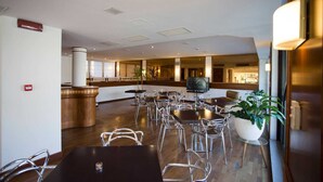 A spacious indoor area with multiple tables and chairs, a large potted plant, and a television on a stand.