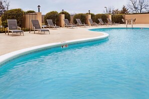 Una piscina al aire libre, sillones reclinables de piscina