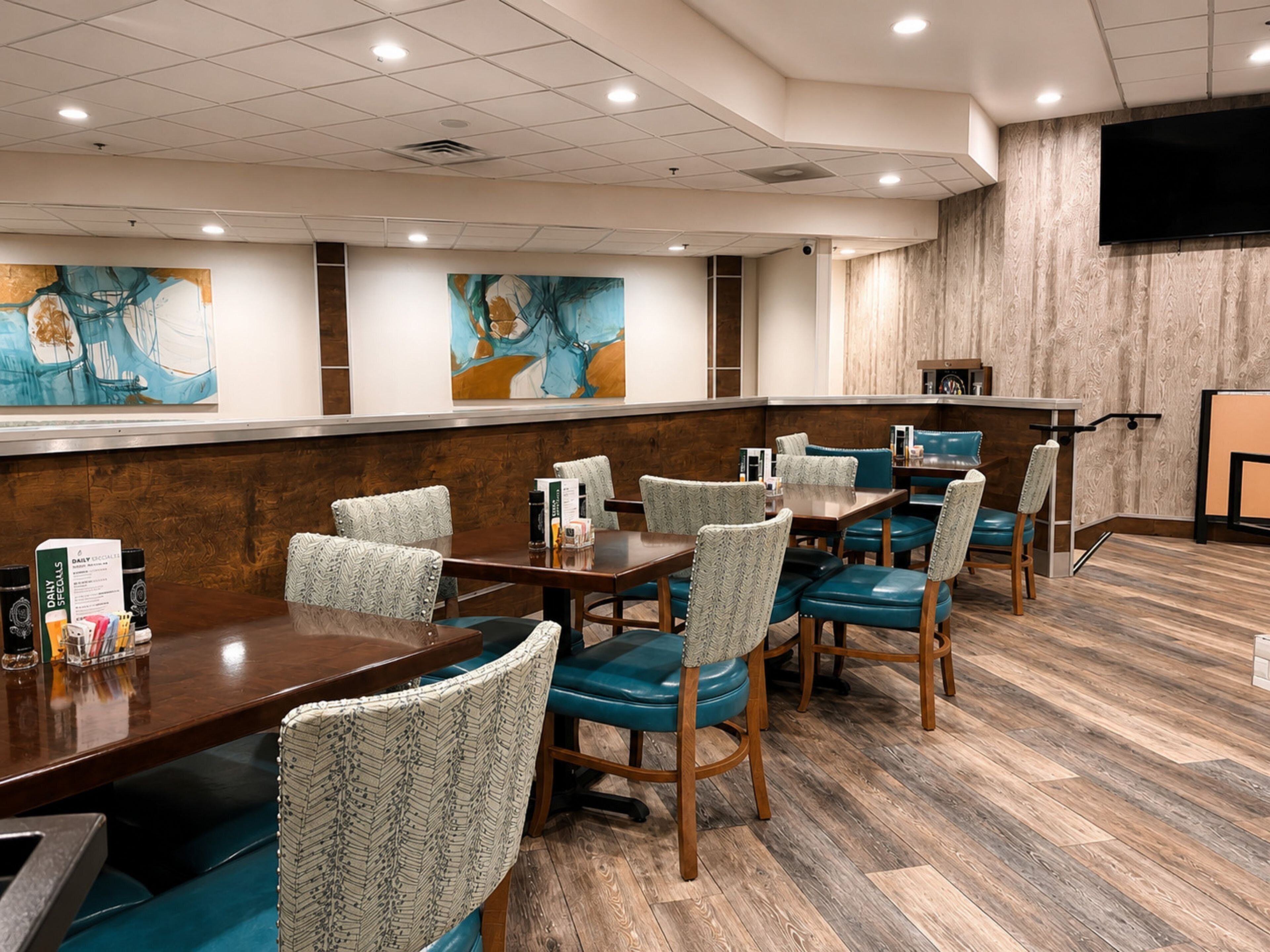 A hotel conference room with wooden tables, patterned chairs, and abstract wall art.