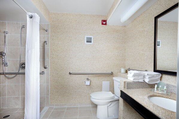 A bathroom with a shower, toilet, and sink, featuring a patterned wall and a mirror.