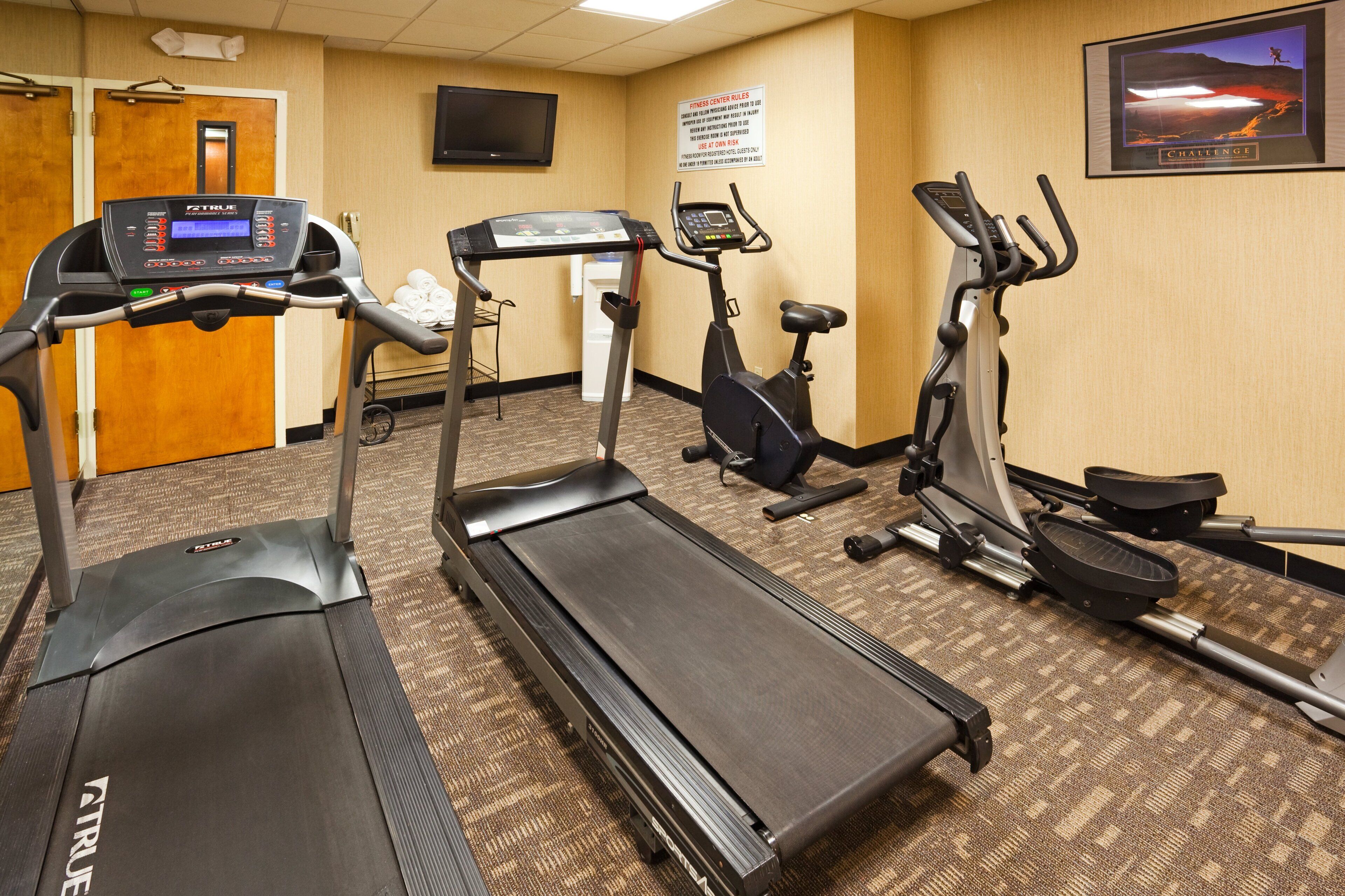 A fitness center with treadmills, stationary bikes, and a wall-mounted television.