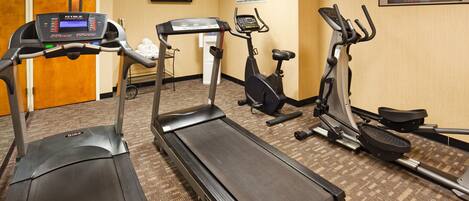A fitness center with treadmills, stationary bikes, and a wall-mounted television.