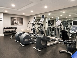 A gym with various exercise machines, a rack of dumbbells, and a clock on the wall. - Holiday Inn Johnson City by IHG (Johnson City)