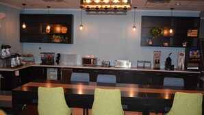 Una cocina moderna con una encimera amplia, taburetes de bar y varios electrodomésticos como un microondas y una cafetera.