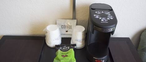 A coffee maker, two coffee pods, and a decaf coffee packet on a table.